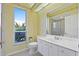 Bright bathroom featuring a vanity with sink, toilet, and a mirror; natural light from a large window at 13783 Palmetto Point Ct, Port Charlotte, FL 33953