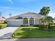 Well-maintained single-story home featuring a lush lawn, palm trees and a two-car garage at 13783 Palmetto Point Ct, Port Charlotte, FL 33953