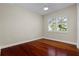 Bedroom with hardwood flooring and view of plantation shutters with green foliage at 143 Tropicana Dr # 1012, Punta Gorda, FL 33950