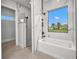 Modern bathroom featuring a soaking tub, luxurious marble tile, and a window with scenic views at 15 Tournament Rd, Rotonda West, FL 33947