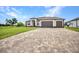 An exterior daytime view of a well-maintained single-story home with a three-car garage and brick driveway at 15 Tournament Rd, Rotonda West, FL 33947