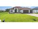 Well-maintained single-story home with manicured lawn, dark trim and a three-car garage at 15 Tournament Rd, Rotonda West, FL 33947