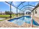 A beautiful screened in pool overlooks a pond with blue skies above at 15 Tournament Rd, Rotonda West, FL 33947