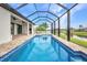 A screened-in pool with brick patio, adjacent to an outdoor kitchen, overlooks a pond at 15 Tournament Rd, Rotonda West, FL 33947