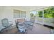 Comfortable screened lanai seating area with three chairs, a table, and an additional cushioned bench at 1596 Hayworth Rd, Port Charlotte, FL 33952