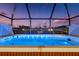 Inviting hot tub beneath a screened enclosure, offering stunning views of the twilight sky and surrounding landscape at 16032 Galiano Ct, Punta Gorda, FL 33955