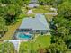 Aerial view of a home with a screened pool, lush green lawn, and mature landscaping at 17396 Cox Ave, Port Charlotte, FL 33948