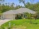 Inviting single-story home with a well-kept lawn, mature plants, and a two-car garage at 17396 Cox Ave, Port Charlotte, FL 33948