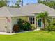 Well-maintained single-story home with a lush green lawn, inviting entrance, and mature landscaping at 17396 Cox Ave, Port Charlotte, FL 33948
