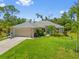 Charming single-story home featuring a well-manicured lawn, attached garage, and tasteful landscaping at 17396 Cox Ave, Port Charlotte, FL 33948