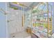 Tiled walk-in shower with glass enclosure, gold hardware and shelving for towels and toiletries at 17396 Cox Ave, Port Charlotte, FL 33948
