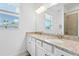 Bright bathroom with dual sinks, granite countertops, white cabinets, and a large mirror at 17629 Palmetto Pass Ln, Punta Gorda, FL 33982