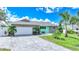 Charming single-story home featuring stone accents, a paved driveway, and lush landscaping with palm trees at 192 Danforth S Dr, Port Charlotte, FL 33980
