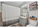 Cozy bathroom with gray vanity, updated fixtures, mirror, and decorative shelving above the toilet at 2465 Deedra St, Port Charlotte, FL 33952