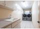 Modern laundry room with washer, dryer, sink, cabinets, and ample storage space at 25538 Rampart Blvd, Punta Gorda, FL 33983