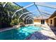Beautiful screened-in pool area featuring a waterfall, lush plants, and an adjacent spa for ultimate relaxation at 25538 Rampart Blvd, Punta Gorda, FL 33983