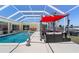 Relaxing poolside patio area features ample seating, a retractable awning, and serene waterfront views at 259 Fields Ter, Port Charlotte, FL 33952