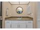 Bathroom vanity with a granite countertop, white cabinets, and a circular mirror at 3225 Magnolia Way, Punta Gorda, FL 33950