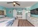 Light-blue main bedroom with a decorative ceiling fan, TV, dresser, and ensuite bathroom with a barn door at 3225 Magnolia Way, Punta Gorda, FL 33950