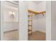 Walk-in closet with custom wooden shelving and beige carpet, adjacent to a bathroom with white cabinets at 3314 Wood Thrush Dr # 124, Punta Gorda, FL 33950