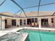 This backyard features a spa and pool surrounded by a covered, screened-in patio and lush landscaping at 3518 Terin Ct, Punta Gorda, FL 33950