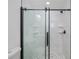 The bathroom features a glass shower with black hardware, white marble walls and pebble stone flooring at 359 Salisbury St, Port Charlotte, FL 33954