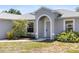 Close up of the home's entrance with an arched doorway, well-maintained landscaping, and natural light at 3886 Cincinnati St, North Port, FL 34286