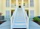 Inviting condo building with bright yellow exterior, white staircase, and neatly landscaped grounds at 410 Cerromar S Cir # 240, Venice, FL 34293