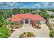 Aerial view of grand Mediterranean-style home with circular driveway, lush landscaping, and tile roof at 4409 Crews Ct, Port Charlotte, FL 33952