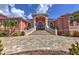 Grand pink two-story home with a paver driveway, manicured landscaping, and an elegant front entrance with a stone staircase at 4409 Crews Ct, Port Charlotte, FL 33952