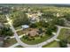 Wide aerial view of a single story home with a pool, long driveway, and surrounded by lush greenery at 4443 Abcor Rd, North Port, FL 34286