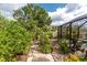 Stone path leads to the screened pool surrounded by lush landscaping, flowers and tropical plants at 4443 Abcor Rd, North Port, FL 34286