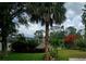 Lush backyard featuring mature palm and blooming trees, with a white fence at 4443 Abcor Rd, North Port, FL 34286