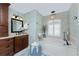 Charming bathroom featuring dark wood vanity, chandelier lighting, and a luxurious bathtub at 4443 Abcor Rd, North Port, FL 34286