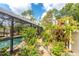 Screened pool with stone pathway surrounded by a garden with lush landscaping and colorful flowers at 4443 Abcor Rd, North Port, FL 34286