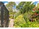 Walkway showcases lush landscaping and garden beds leading toward the screened pool area in the backyard at 4443 Abcor Rd, North Port, FL 34286