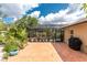 Paver patio featuring tropical plants and a screened pool, plus grill and view of blue cloudy skies at 4443 Abcor Rd, North Port, FL 34286