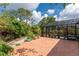 Paver patio showcasing tropical plants and a screened pool, beneath sunny skies at 4443 Abcor Rd, North Port, FL 34286