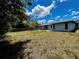 A sunny backyard featuring fence, mature trees, and a view of the house's rear exterior at 5498 Montego Ln, Port Charlotte, FL 33981