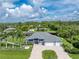 Stunning aerial view of a home with a three-car garage, a well-kept lawn, and lush greenery surrounding the property at 1025 Cheshire St, Port Charlotte, FL 33953