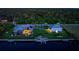 Aerial nighttime view showcasing a waterfront home with a screened pool, palm trees, and boat dock at 1025 Cheshire St, Port Charlotte, FL 33953