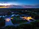 Aerial view of a waterfront property at dusk, featuring outdoor lighting and serene setting at 1025 Cheshire St, Port Charlotte, FL 33953