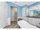 This bathroom has blue walls, a soaking tub, granite counters, and modern wood look flooring at 1025 Cheshire St, Port Charlotte, FL 33953