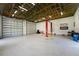 Expansive garage with epoxy flooring, offering plenty of room for storage, a vehicle lift, and multiple garage door access at 1025 Cheshire St, Port Charlotte, FL 33953