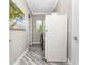 Hallway with a white refrigerator, utility equipment, neutral walls, and wood-look floors at 1025 Cheshire St, Port Charlotte, FL 33953