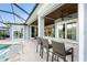 Covered outdoor patio with a wet bar, seating, and access to the pool and screened-in lanai at 1025 Cheshire St, Port Charlotte, FL 33953