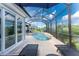 A screened-in swimming pool with deck chairs, lush landscaping, and a view of the water at 1025 Cheshire St, Port Charlotte, FL 33953