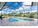 A screened-in swimming pool with a waterfall feature, surrounded by a tiled deck and lush landscaping at 1025 Cheshire St, Port Charlotte, FL 33953