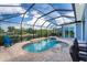 A screened-in swimming pool and spa with lush landscaping, deck chairs, and a view of the water at 1025 Cheshire St, Port Charlotte, FL 33953