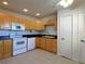 Clean kitchen space with wood cabinets, white appliances, and tiled flooring at 1217 Aqui Esta Dr # 5, Punta Gorda, FL 33950